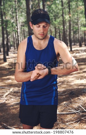 Man looking at stopwatch to check gps pace and time on trail run