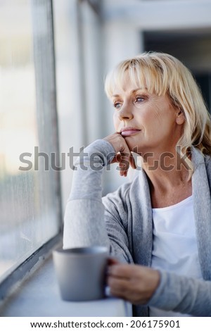 Beautiful woman looking out the window with a hot beverage