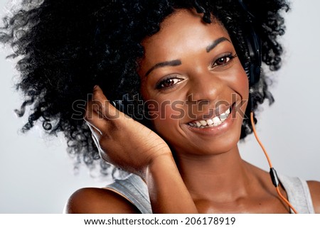 Closeup portrait of a smiling african woman with afro and headphones against isolated background
