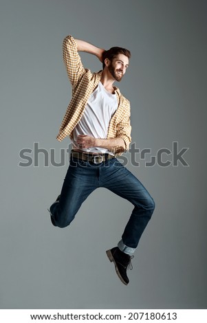 Fashion model man with hipster beard jumping and having fun in studio