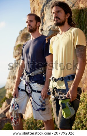 Two men looking at the view from the mountain with their rock climbing equipment on