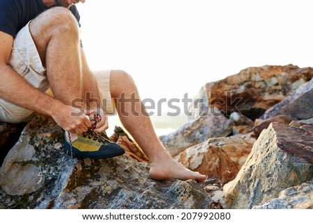 Hiker sitting on a rock tying up his shoe laces with copyspace
