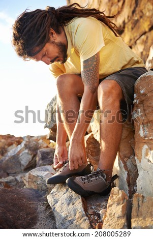 Hiker with dreadlocks tying his shoelaces
