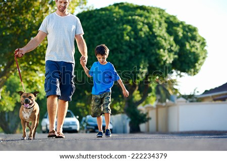 A father walking with his dog and his son in the suburbs