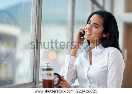Happy businesswoman on work call with coffee and window smiling