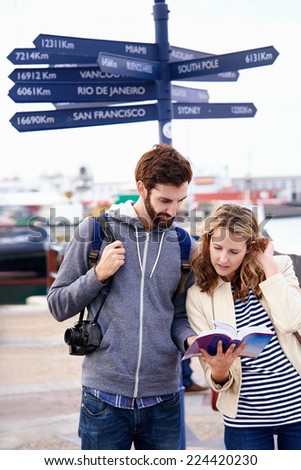 couple on travel holiday at sign with guide book