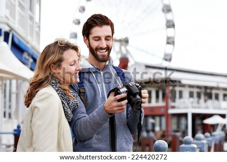 young couple taking pictures on holiday at tourist attraction