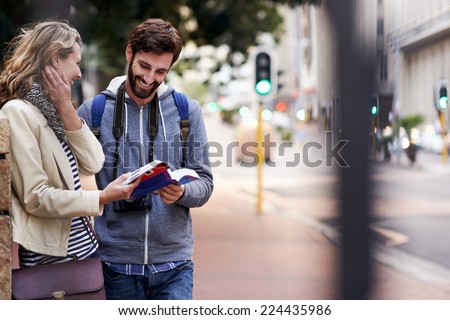 travel couple walking around city on vacation with guide book having fun