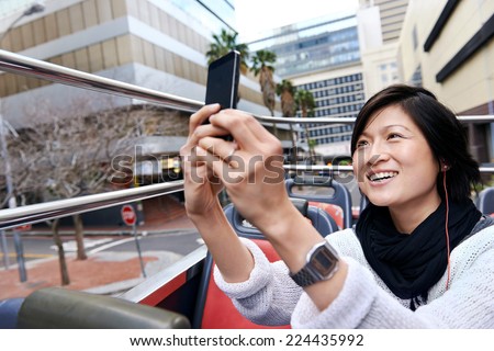 Asian tourist chinese woman having fun on open top bus in city tour