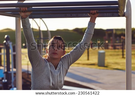 young athletic fitness woman working out at outdoor gym doing pull ups at sunrise