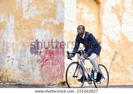Black african mad riding bicycle in urban city commuting with speed and hipster trendy transportation