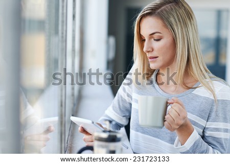 Young businesswoman working on tablet computer while drinking coffee in the office