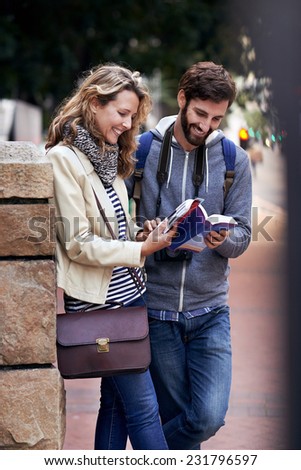 travel couple walking around city on vacation with guide book having fun