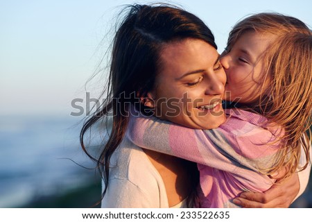 Unconditional love between mother and daughter hugging and embrace with a kiss and cuddle outdoors having fun