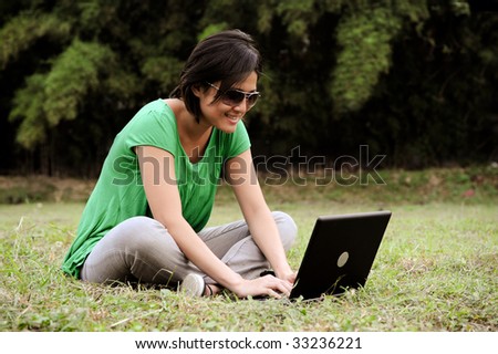 An asian girl writes an email in the park