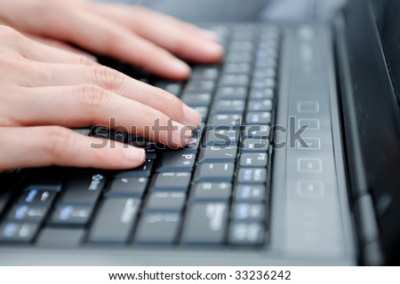 Female fingers type on a laptop.
