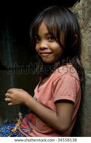 SIEM REAP, CAMBODIA - CIRCA JANUARY 2009: A young unidentified girl poses for a portrait as she makes a souvenir necklace at Angkor Wat temple circa January 2009 in Siem Reap, Cambodia.