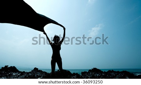 Girl stands in the wind along the ocean edge