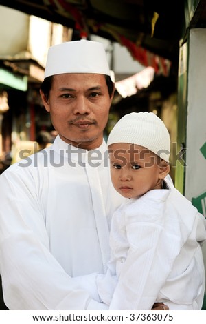 JAKARTA, INDONESIA - SEPTEMBER 20: A man and his son pose for a picture on their way to prayer at the mosque on Hari Raya, the end of a month of fasting called Ramadan September 20, 2009 in Jakarta.