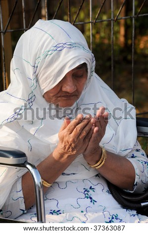 JAKARTA, INDONESIA - SEPTEMBER 20: An elderly muslim woman prays outside a mosque on Hari Raya, the end of a month of fasting called Ramadan September 20, 2009 in Jakarta.