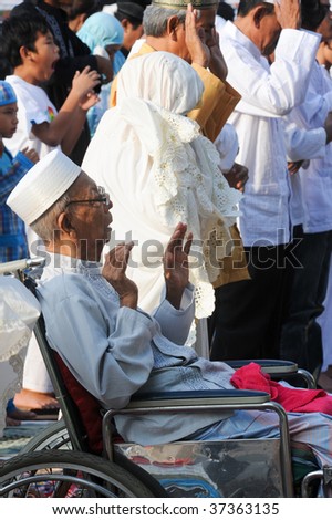 JAKARTA, INDONESIA - SEPTEMBER 20: A Muslim man in a wheelchair prays with fellow Muslims outside a mosque in Jakarta on Hari Raya, the end of a month of fasting called Ramadan September 20, 2009 in Jakarta.