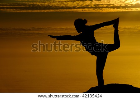 Girl does yoga at sunset on top of a mountain
