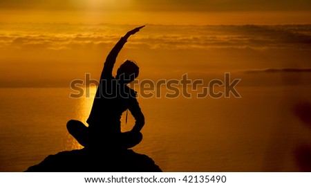 Girl does yoga at sunset on top of a mountain