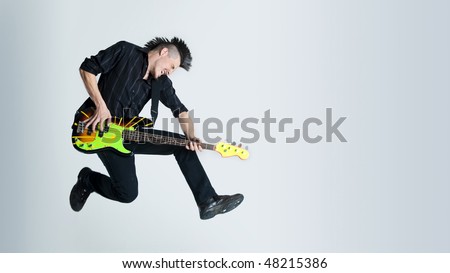Awesome mohawk man jumps with his guitar in studio