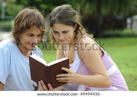 Attractive couple read together in the park