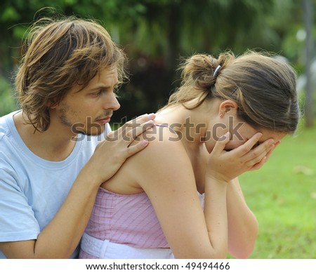 Man consoles his crying girlfriend in the park