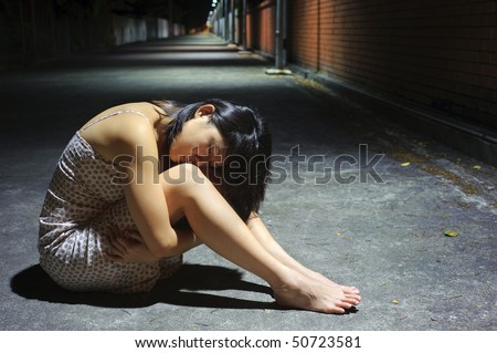 Tired Asian girl rests her head on her knees