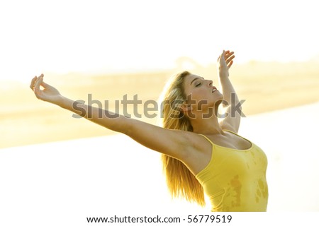 Healthy young woman stretches her arms out at sunset