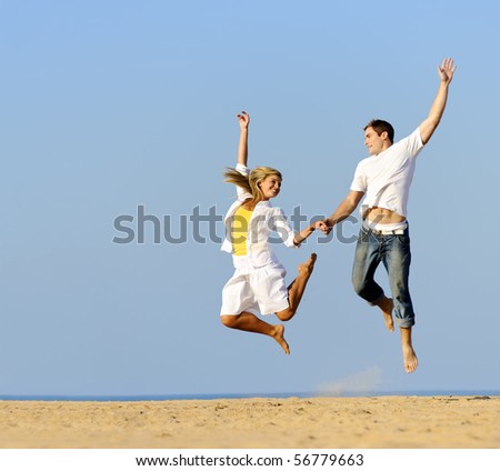 Playful couple jumping and smiling on the beach