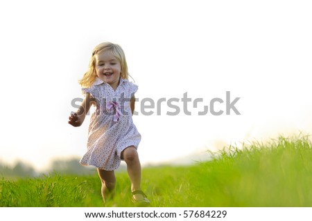 Young girl runs through a field, happy and having fun.