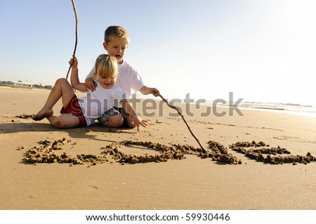 Lovely young brother and sister write words in the sand together