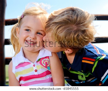 Young boy gives his sister a kiss on the cheek