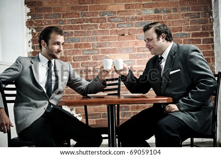 businessmen agree as the cheers with their coffee mugs