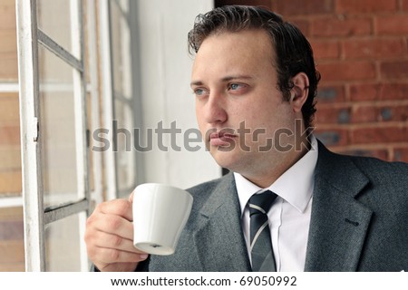 Old style man with coffee at the window while wearing suit