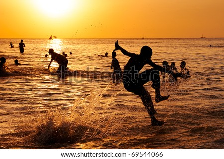 Young boy jumps in the ocean and makes a splash at sunset