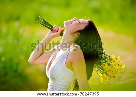 candid adorable girl in white dress is carefree with flowers in green field during spring.