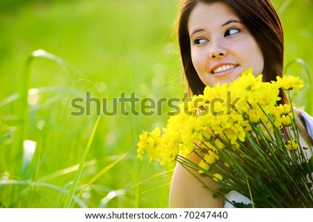 Adorable girl with flowers poses in a field during summer afternoon.