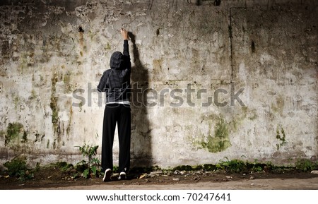 Youngster with spray paint and an empty wall for graffiti