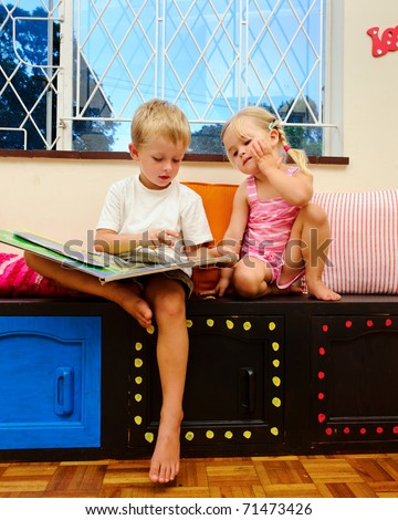 little girl listens to her big brother reading a childrens book at school