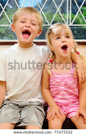 young children shouting for joy with arm around shoulder