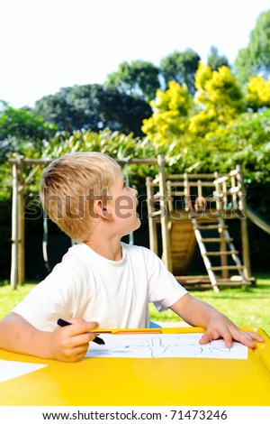 young boy looks at the sky to see how he wants to draw the clouds with wax crayons