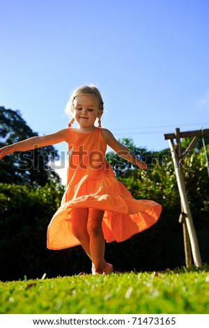 beautiful girl twirls in the sunset in her orange dress with blonde hair in pigtails