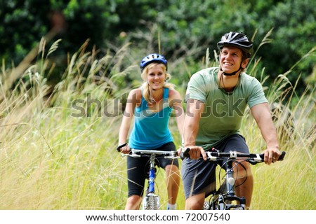 Happy couple riding bicycles outside, healthy lifestyle fun concept