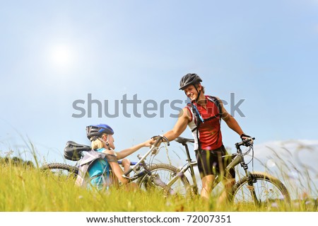 young man helps a fellow cyclist who has fallen over while mountain bicycle outdoors