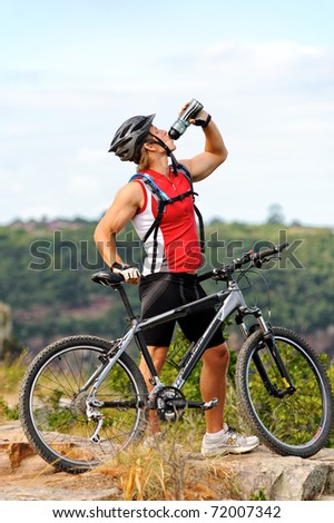 young man drinks water to quench thirst after a mountain bike cycle