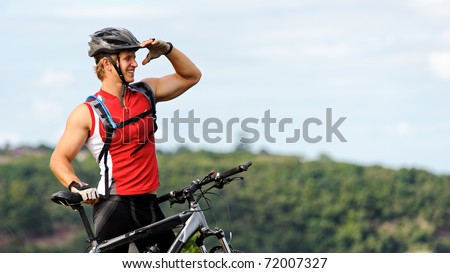 man looks out into the distance while standing outdoors with mountain bike